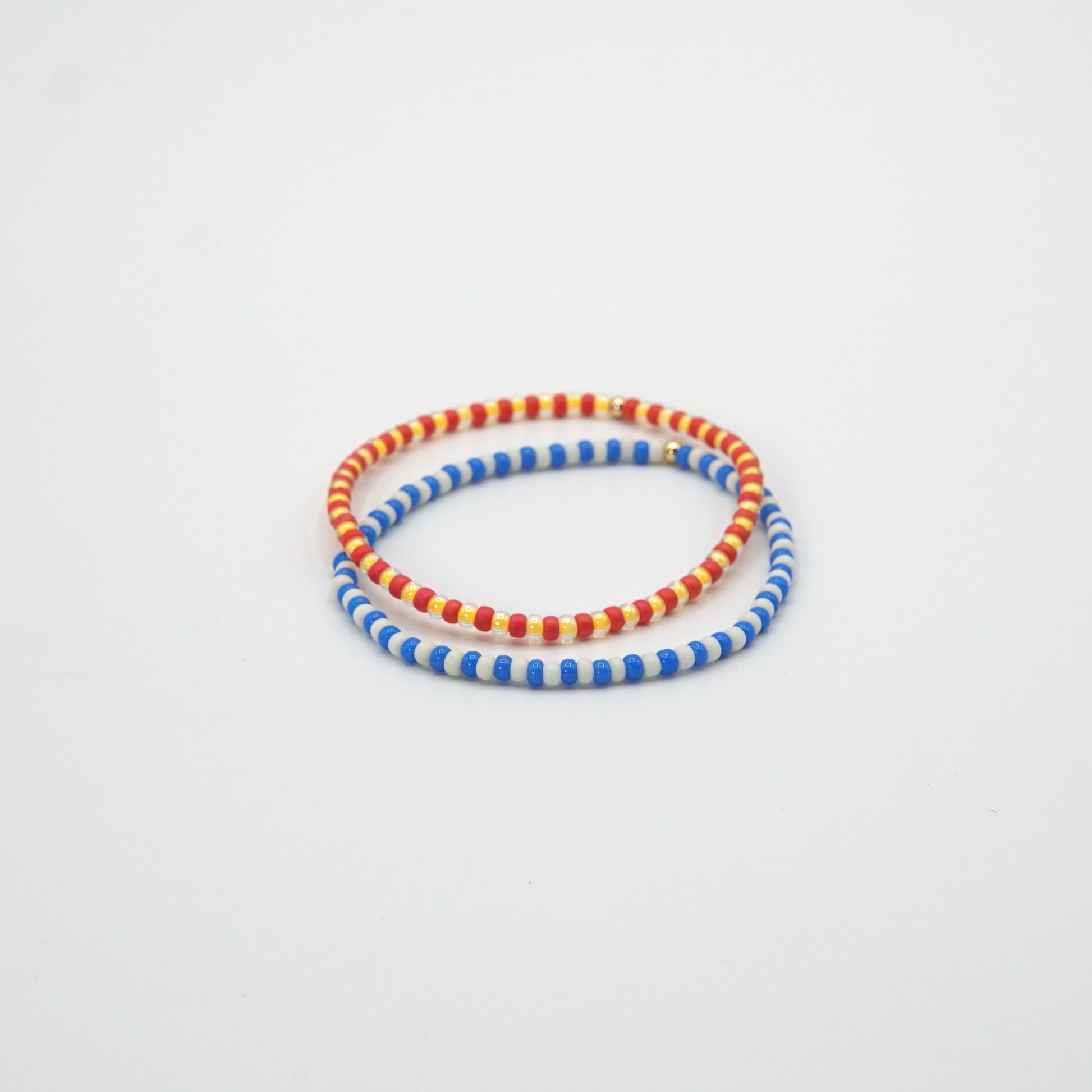 Elastische 17,5 cm lange Armbänder NAGOMI mit kontrastierenden Glasperlen und einer zarten 14-Karat-Goldfilled-Perle.