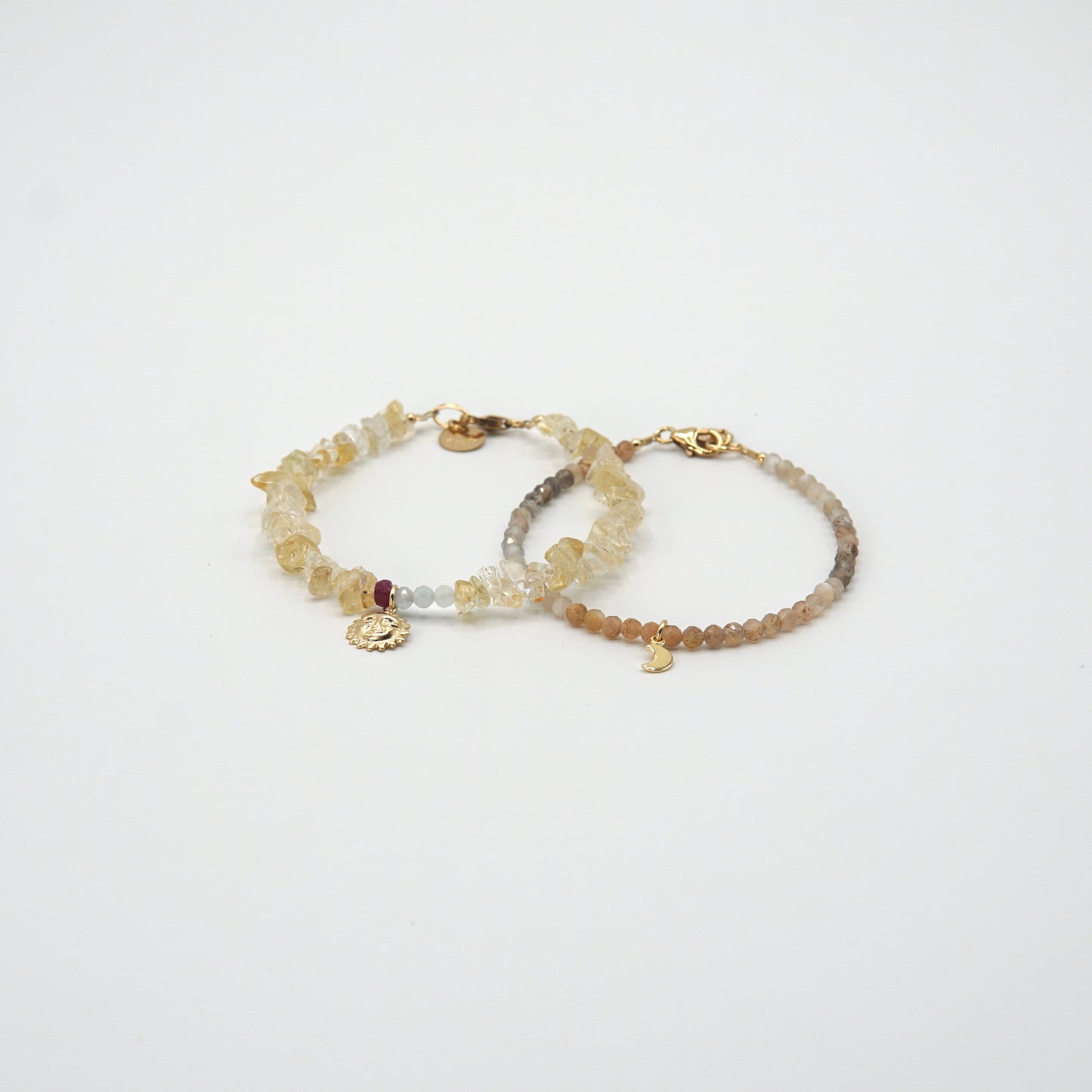 Armband 'SOLEIL' mit Citrinen, Rubin, Aquamarinen und goldenem Sonnenanhänger, strahlend am Handgelenk getragen.