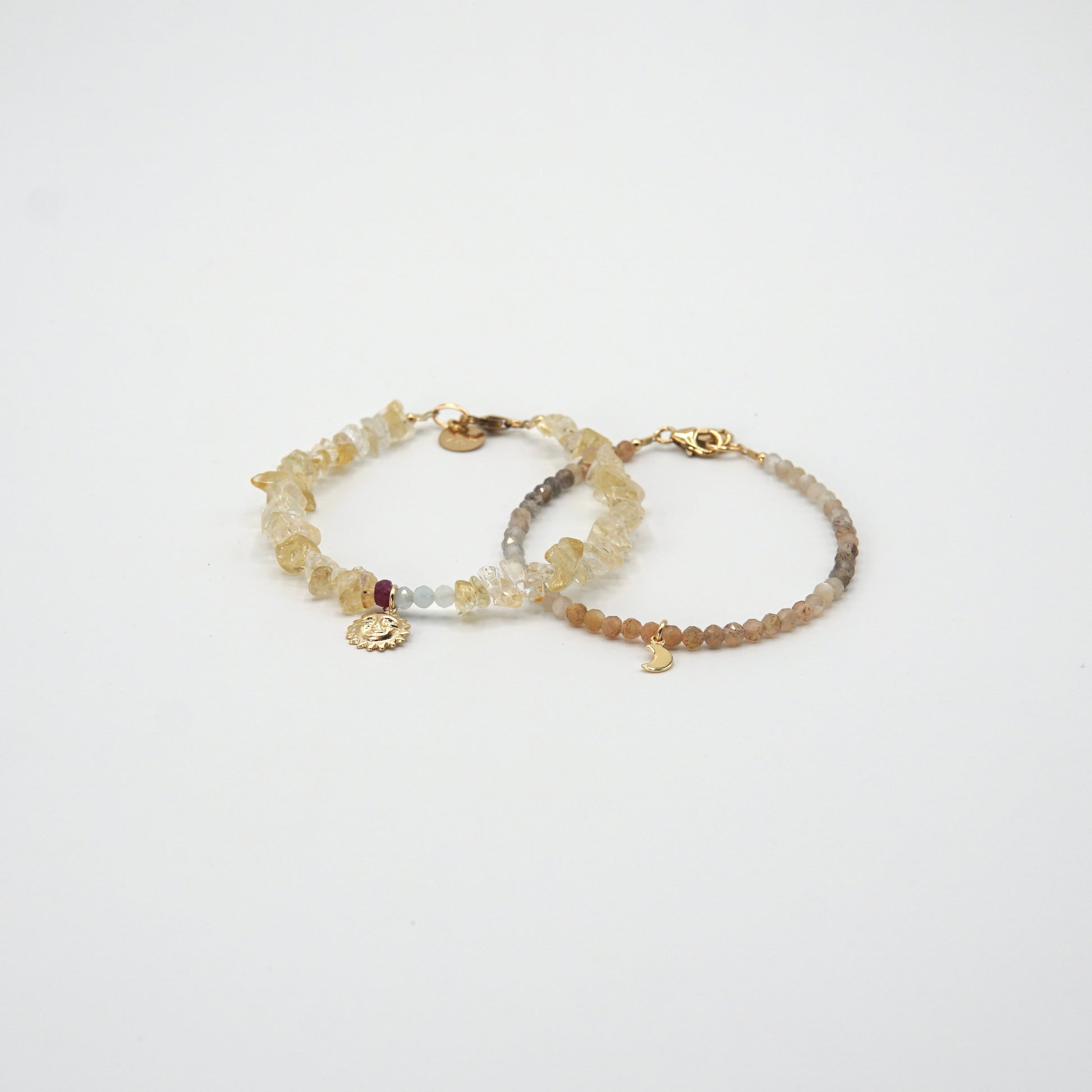 Armband 'SOLEIL' mit Citrinen, Rubin, Aquamarinen und goldenem Sonnenanhänger, strahlend am Handgelenk getragen.