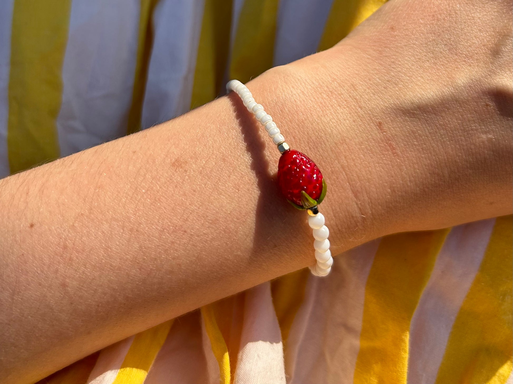 Detailansicht der handgearbeiteten Glasperle des 'STRAWBERRY BABE'-Armbands, umgeben von feinen Glas- und Perlmuttperlen."