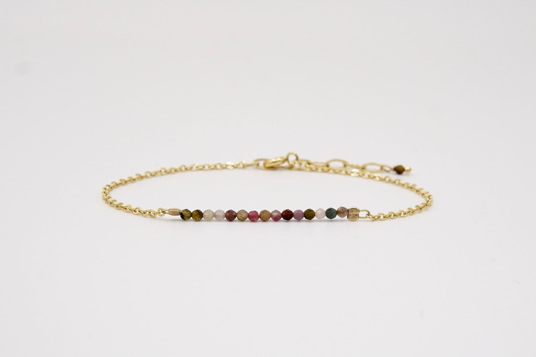 Armband 'PAPILLON' mit schimmernden Turmalin-Perlen und goldener Verlängerungskette am Handgelenk getragen.