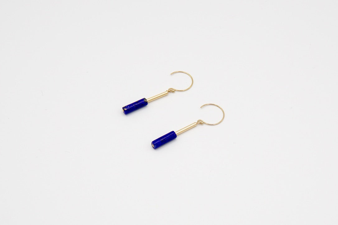 Nahaufnahme der tiefblauen Lapislazuli-Stäbchen der Ohrringe FLAMBEAU BLEU, zeigt die natürliche Maserung und das elegante Design