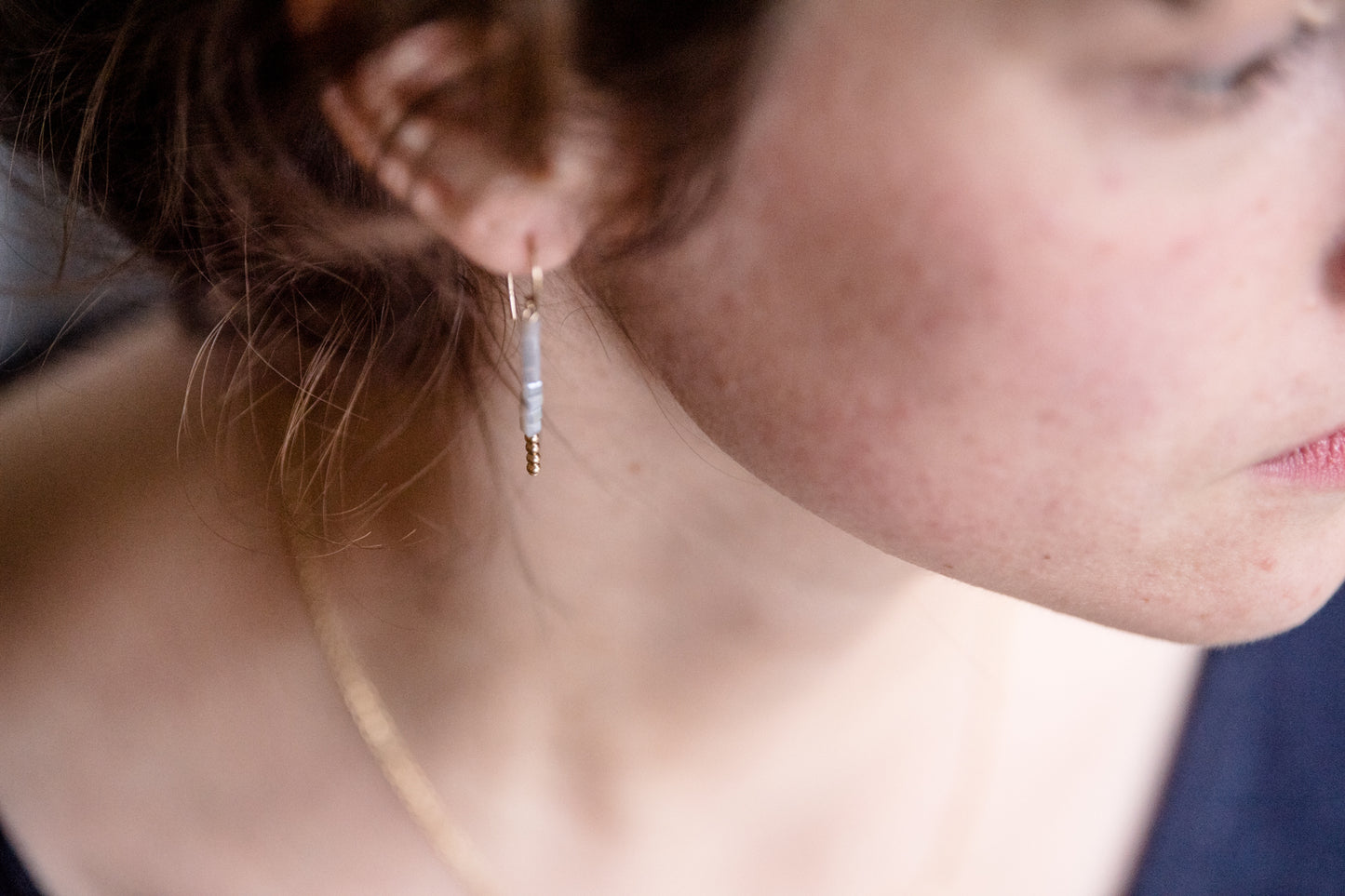 Modell trägt die Ohrringe MINI CUBE, elegante Accessoires mit schlichten Glaswürfeln und goldenen Details.