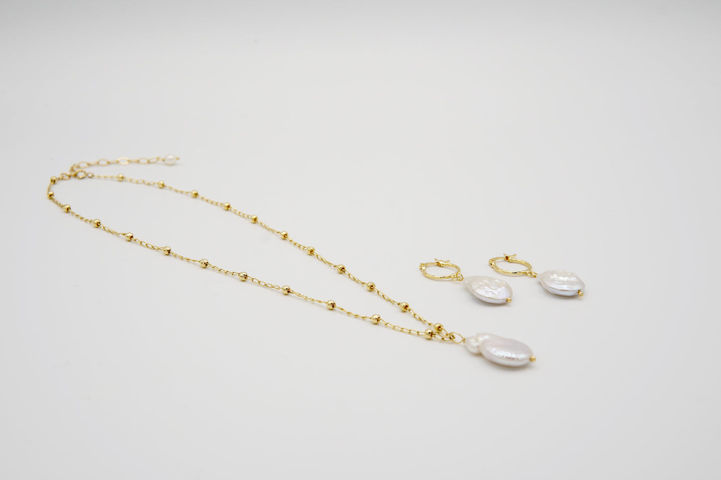 Nahaufnahme der Ohrringe und Kette COLETTE, zeigt die feine Handwerkskunst und das minimalistische Design aus 14 Karat Goldfilled.