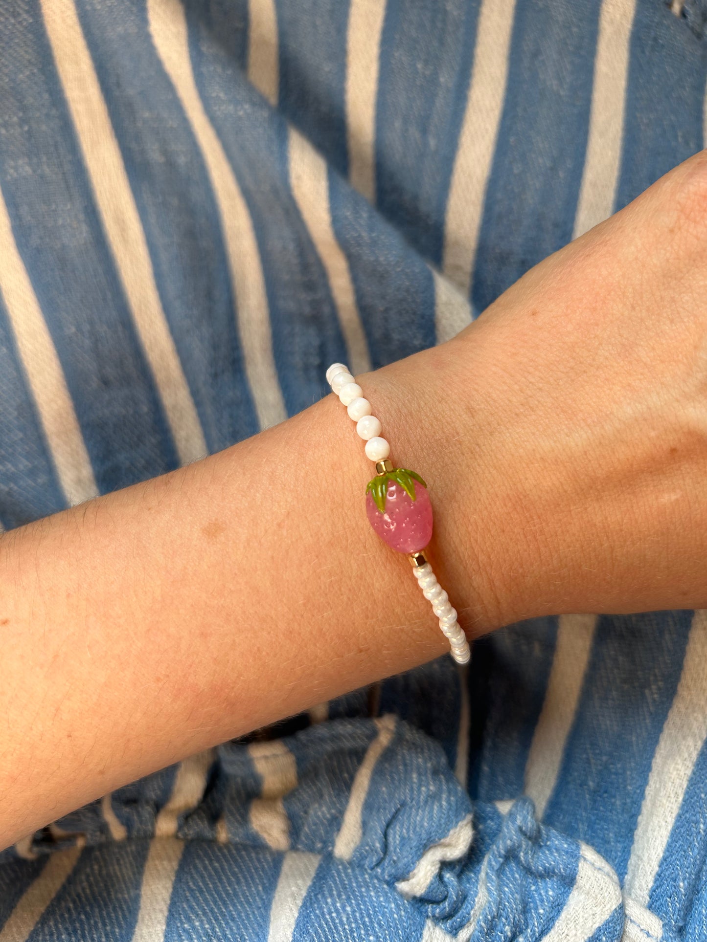Armband 'STRAWBERRY BABE' mit schimmernden Glas- und Perlmuttperlen sowie goldenen Akzenten, elegant am Handgelenk getragen.