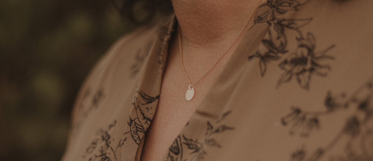 Modell trägt die Kette PLAQUETTE mit goldenem Plättchen-Anhänger, elegantes Accessoire für verschiedene Anlässe