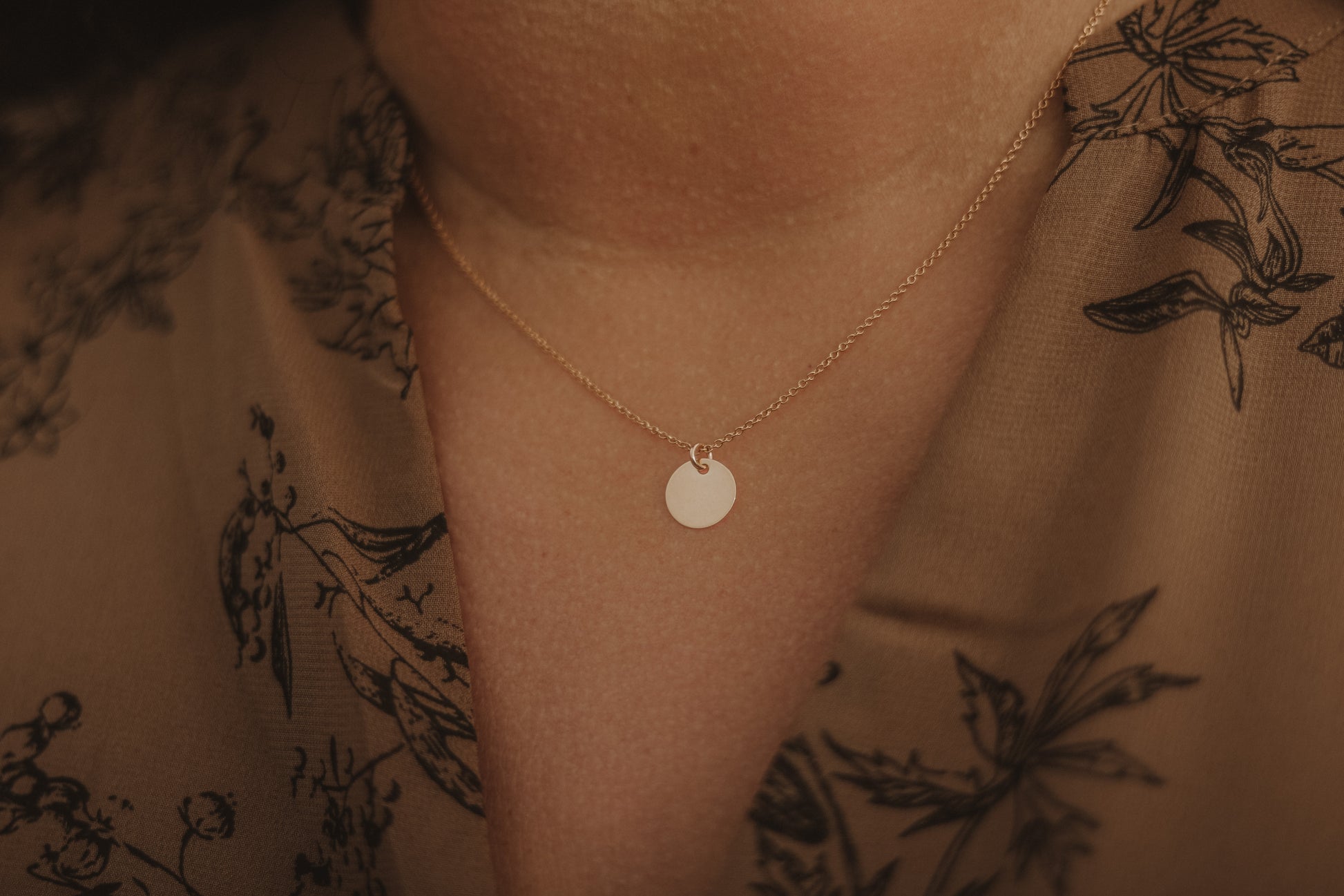 Frontansicht Modell trägt die Kette PLAQUETTE mit goldenem Plättchen-Anhänger, elegantes Accessoire für verschiedene Anlässe