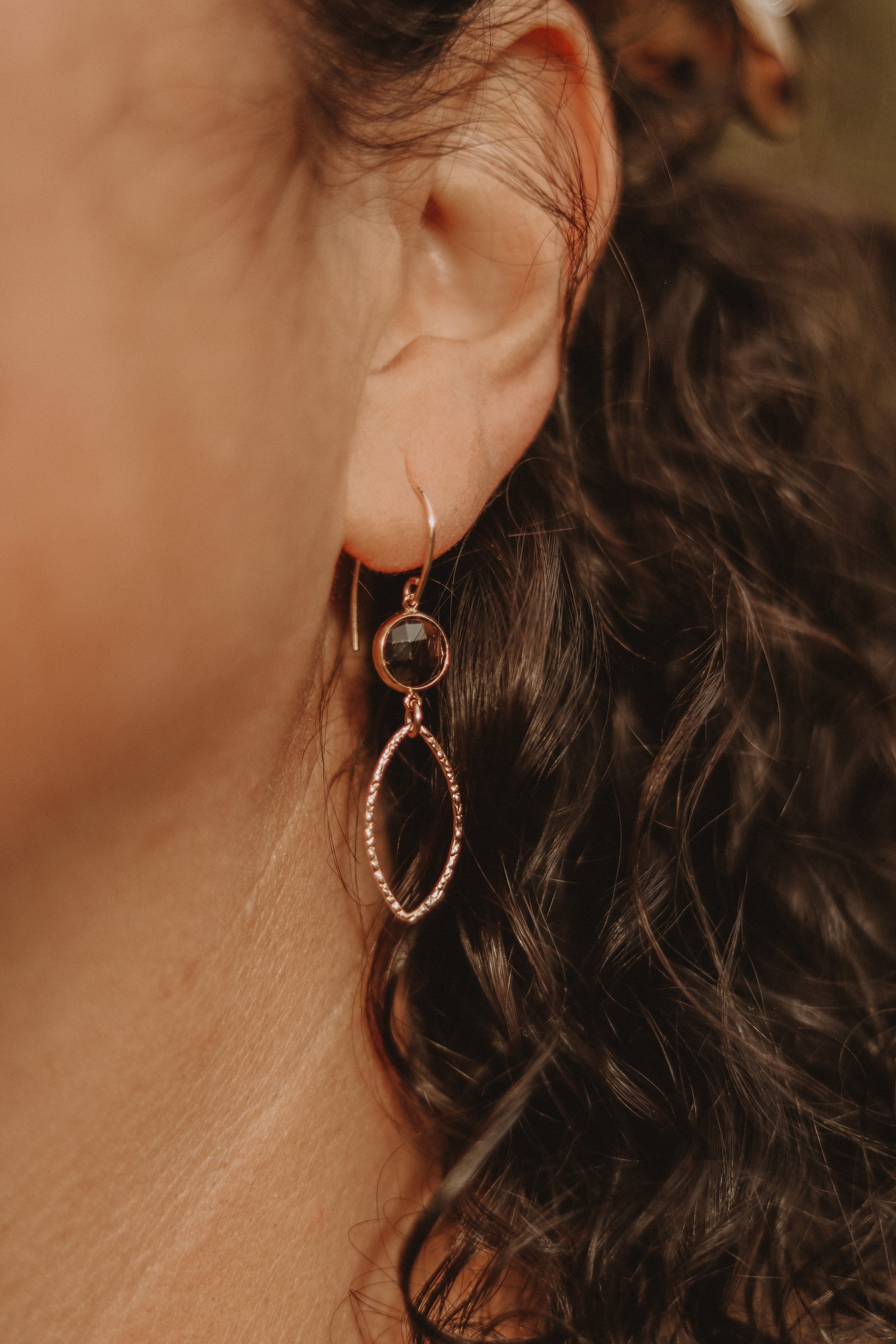 Modell trägt die Ohrringe RÉMY, elegante Accessoires mit schlichten Glasperlen und goldenen Details.