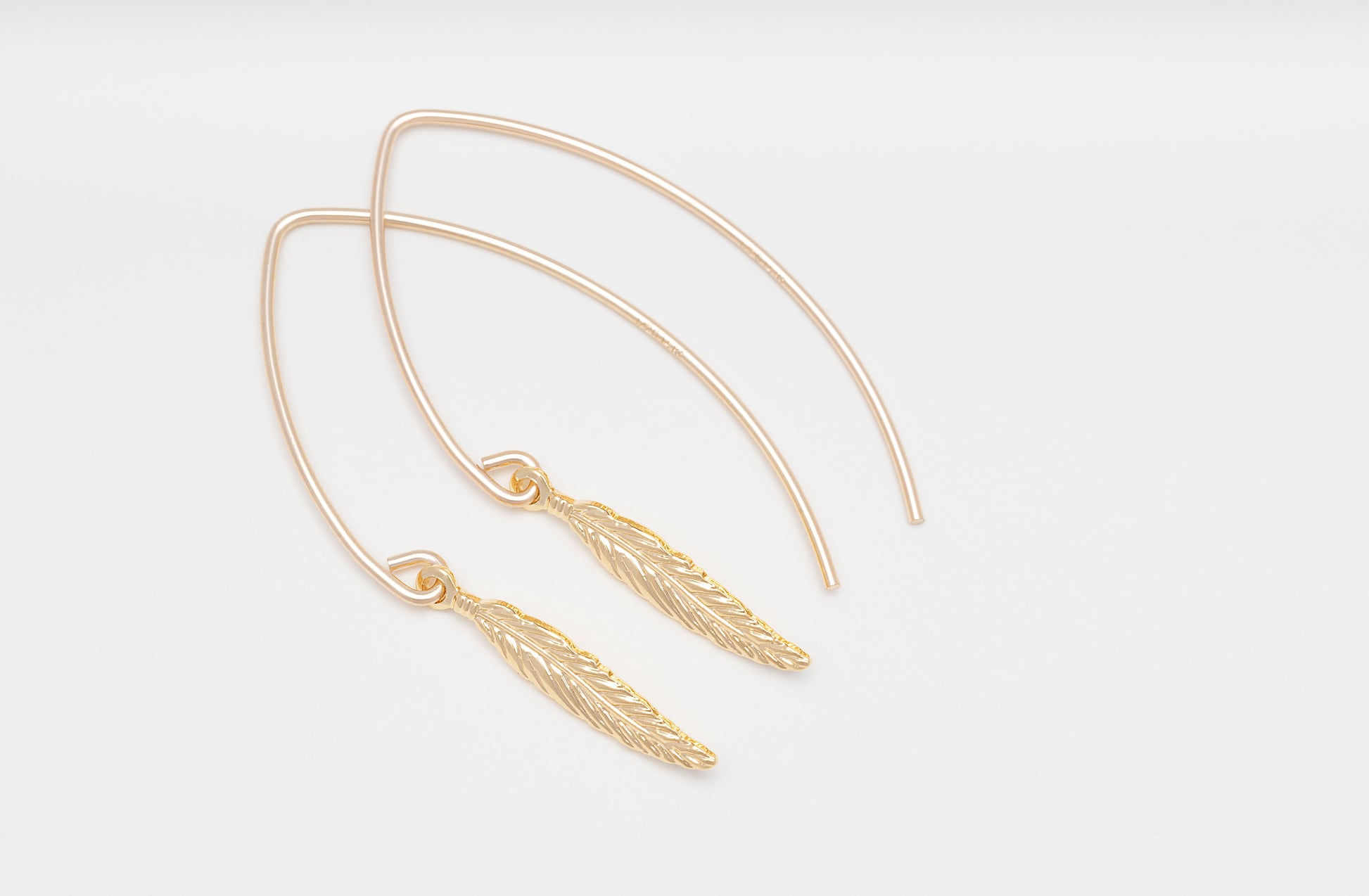 Nahaufnahme der filigranen Feder-Anhänger der Ohrringe PLUME, zeigt die feine Handwerkskunst und das elegante Design
